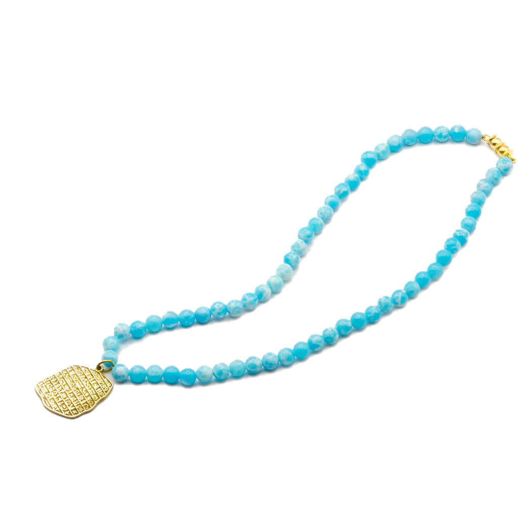 Angled view of handmade Egyptian brass necklace with blue beads and gold pendant