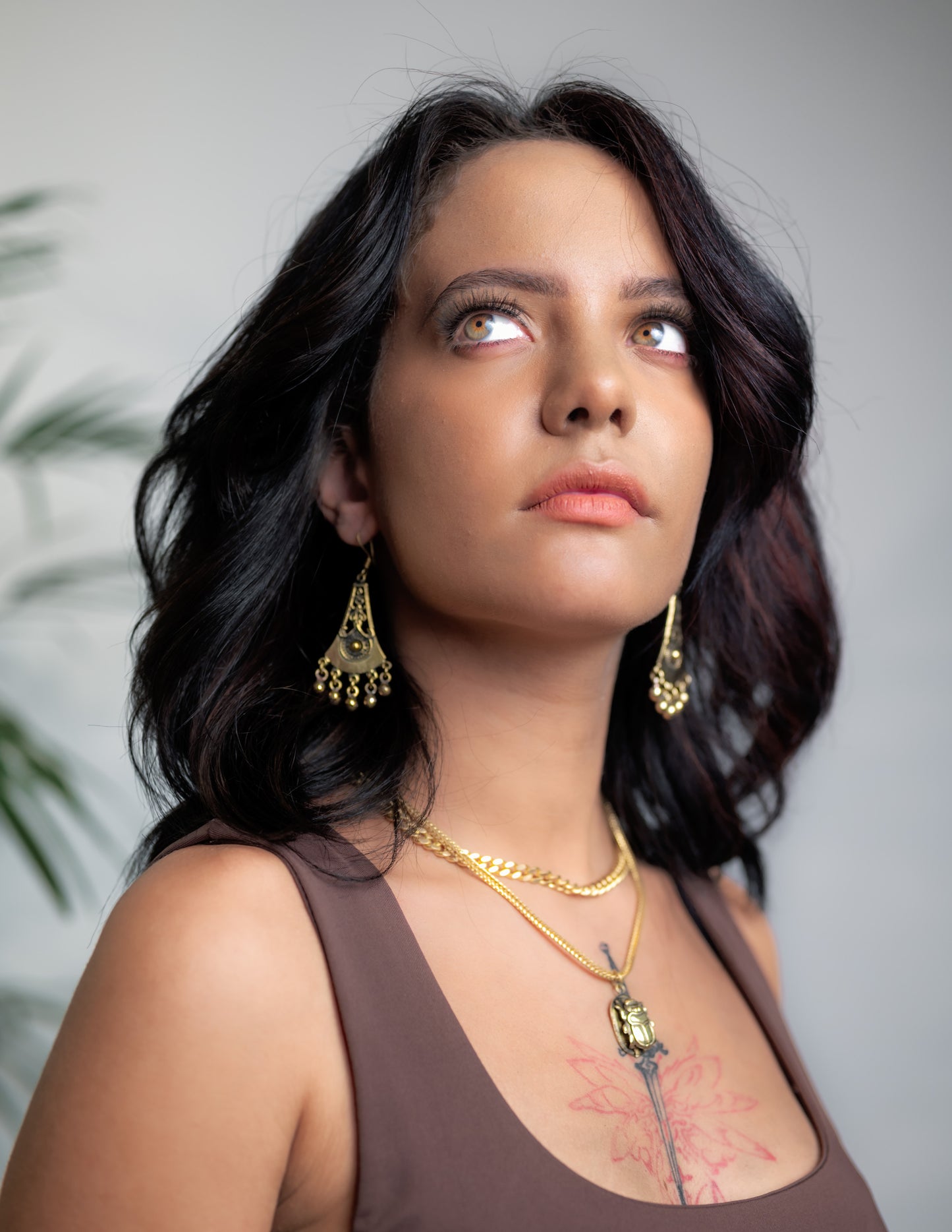 Side profile of model wearing Zahra brass necklace, showing sweeping silhouette and drape along neck